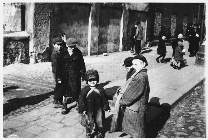 A group of children are gathered on a street corner in the Warsaw ghetto